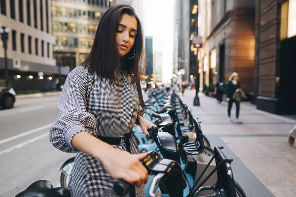 Девушка арендует городской велосипед у велостоянки — стоковое фото