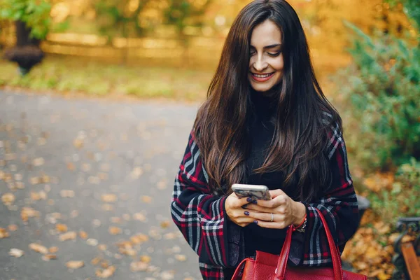 Dívka pomocí její mobil při procházkách v parku — Stock fotografie