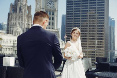 Beyaz elbiseli ve peçeli zarif bir gelin. Mavi takım elbiseli yakışıklı damat. Büyük bir kasabada bir çift