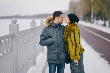 Güneşli bir kış gününde parkta yürüyen mutlu çift.