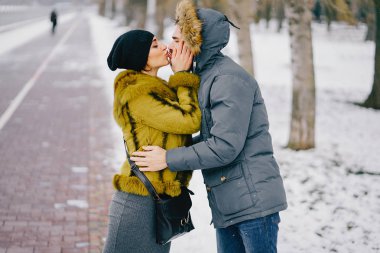 Güneşli bir kış gününde parkta yürüyen mutlu çift.