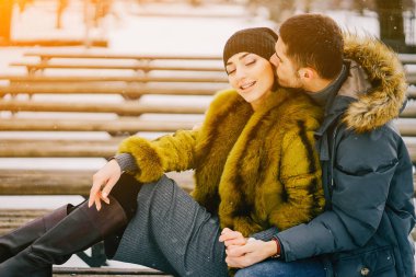 Güneşli bir kış gününde parkta yürüyen mutlu çift.