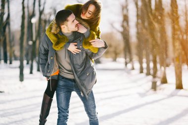 Güneşli bir kış gününde parkta yürüyen mutlu çift.