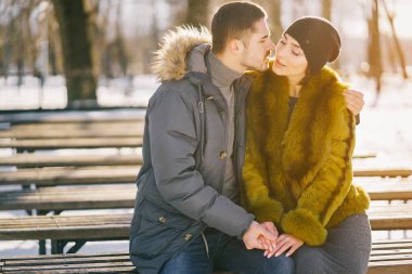 Güneşli bir kış gününde parkta yürüyen mutlu çift.