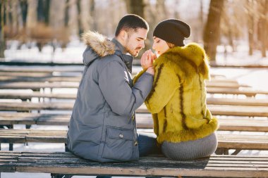 Güneşli bir kış gününde parkta yürüyen mutlu çift.