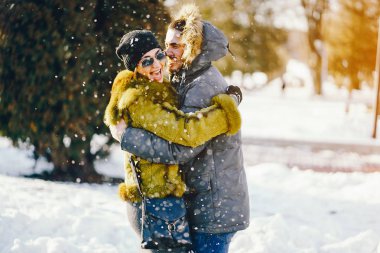 Güneşli bir kış gününde parkta yürüyen mutlu çift.