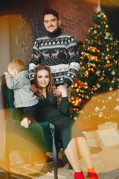 Söt familj sitter nära julgran — Stockfoto