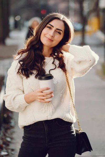 Симпатичная брюнетка в белом свитере в городе — стоковое фото