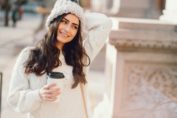 Roztomilá brunetka v bílém svetru ve městě — Stock fotografie