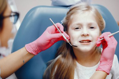 Sevimli küçük kız dişçi ofisinde oturuyor