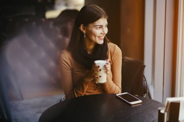 Esmer kız restoranda telefon kullanıyor.