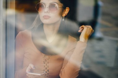 Esmer kız restoranda telefon kullanıyor.