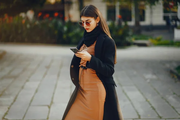 Snygg flicka promenader genom staden när du använder sin telefon — Stockfoto