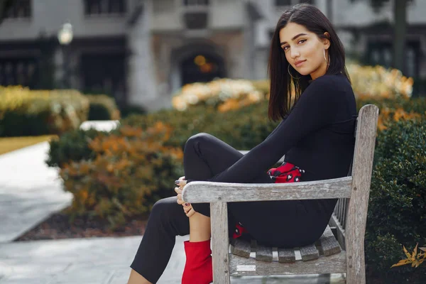 Chica elegante sentada en un banco en la escuela — Foto de Stock