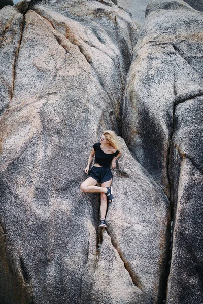 Blond dívka sedí na skalní útvar — Stock fotografie