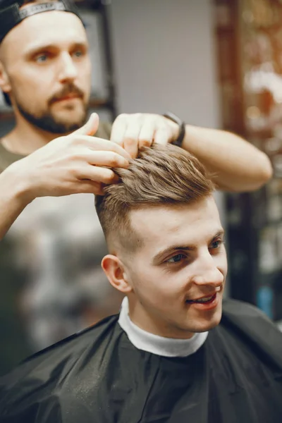 Um homem corta cabelo numa barbearia — Fotografia de Stock