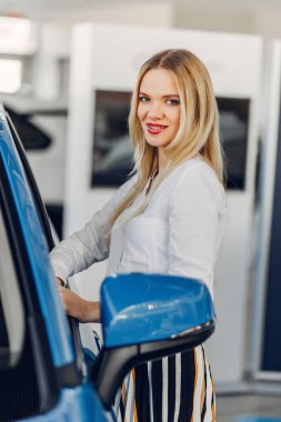 Bir araba galerisinde şık ve zarif bir kadın.