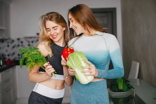 Δύο σπορ κορίτσι σε μια κουζίνα με λαχανικά — Φωτογραφία Αρχείου