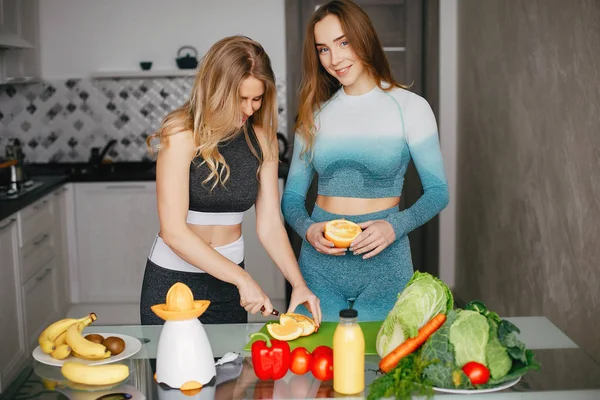 Dva sportovní dívka v kuchyni se zeleninou — Stock fotografie