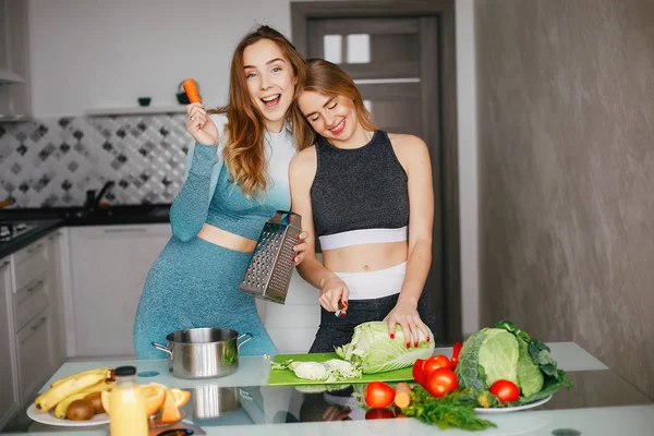Dua gadis olahraga di dapur dengan sayuran — Stok Foto