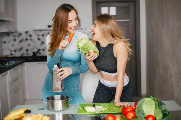 Två sporter flicka i ett kök med grönsaker — Stockfoto
