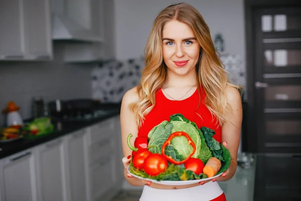 Sport flicka i ett kök med grönsaker — Stockfoto