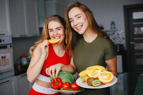 Két sport-lány a konyhában, zöldségekkel — Stock Fotó