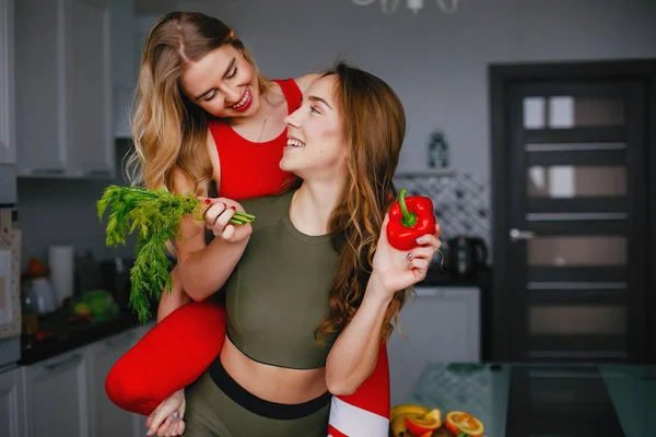 Dois esportes menina em uma cozinha com legumes — Fotografia de Stock