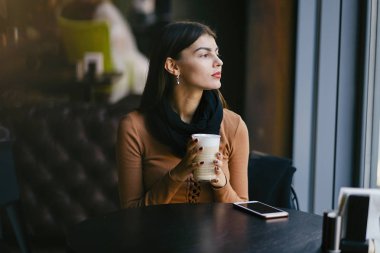 Esmer kız restoranda telefon kullanıyor.