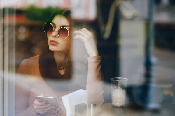 Chica morena usando el teléfono mientras que en un restaurante —  Fotos de Stock