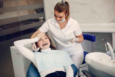 Güzel kız dişçi ofisinde oturuyor.