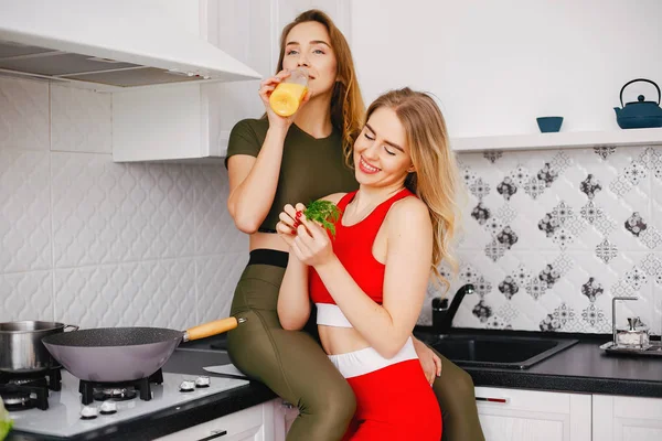 Dois esportes menina em uma cozinha com legumes — Fotografia de Stock