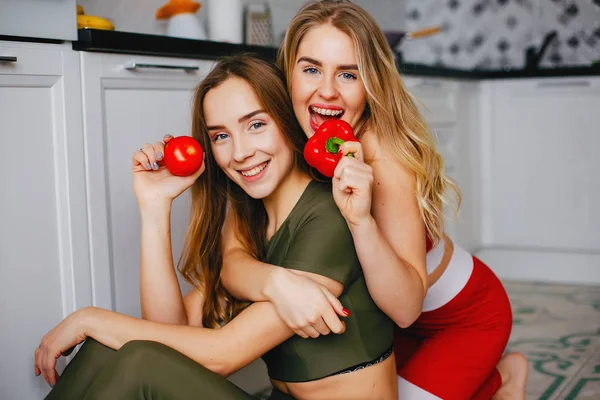 Δύο σπορ κορίτσια σε μια κουζίνα με λαχανικά — Φωτογραφία Αρχείου