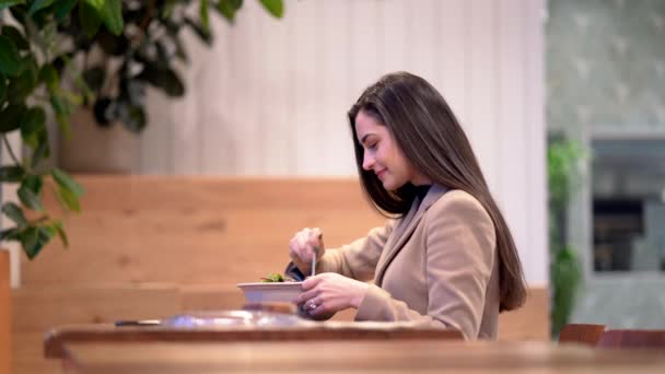 Video de una chica comiendo una ensalada y usando el teléfono celular — Vídeos de Stock