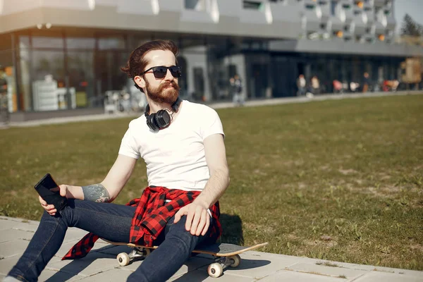 Stylish guy with skate in a summer city — Stock Photo, Image