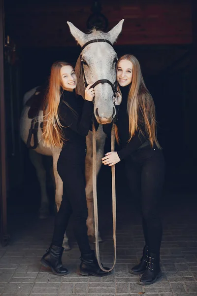 Elegante meisjes met een paard in een ranch — Stockfoto