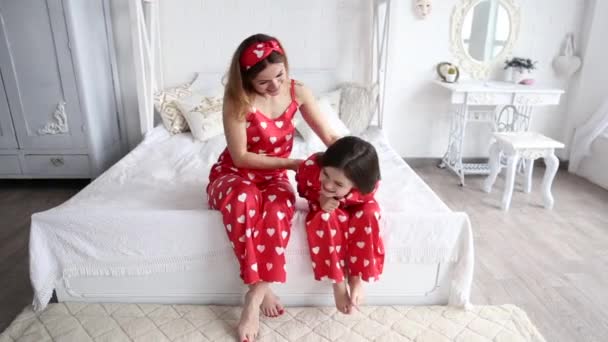 Video of mother and daughter playing in the bedroom in matching pajamas — Stock Video