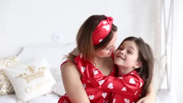Видео матери и дочери, играющих в спальне в одинаковых пижамах — стоковое видео