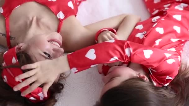 Видео матери и дочери, играющих в спальне в одинаковых пижамах — стоковое видео