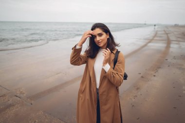 Genç kız sahilde yürüyor.