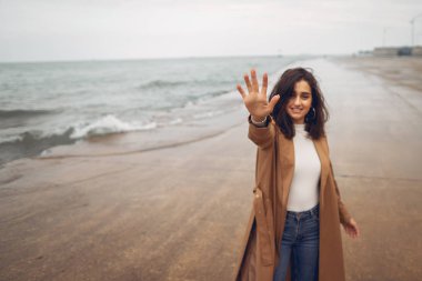 Genç kız sahilde yürüyor.