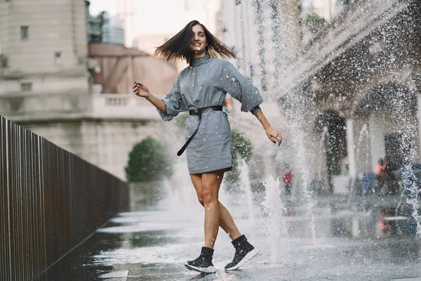 Chica jugando y bailando en una calle mojada — Foto de Stock