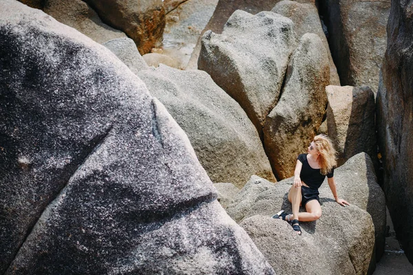 Blond dívka sedí na skalní útvar — Stock fotografie