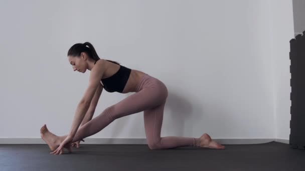 Підходить дівчина займається, роблячи йогу і розтягується — стокове відео