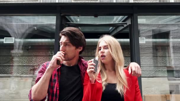 Stílusos pár egy városban. Két ember használja az elektronikus cigarettát. — Stock videók