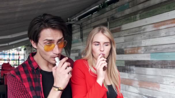 Stylový pár ve městě. Dva lidé používají elektronickou cigaretu — Stock video