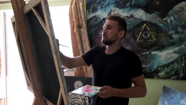 Αρσενικό καλλιτέχνη ζωγραφίζοντας μια εικόνα σε ένα στούντιο — Αρχείο Βίντεο