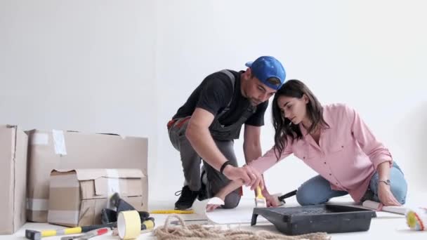 Молодая пара готовится к строительству и покраске стен — стоковое видео
