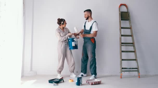 Pareja divirtiéndose mientras trabaja y pintando su nuevo apartamento — Vídeo de stock