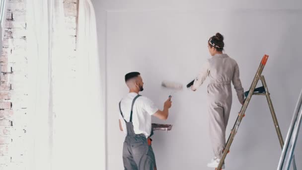 Femme debout sur une échelle tandis que son mari peint le mur — Video